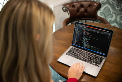 Woman typing code on a laptop computer.