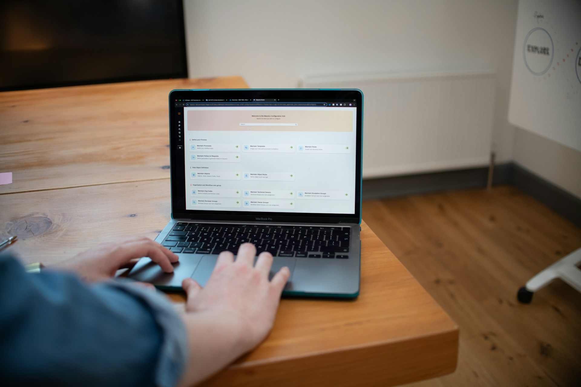 Person typing on a laptop computer on a wooden desk.