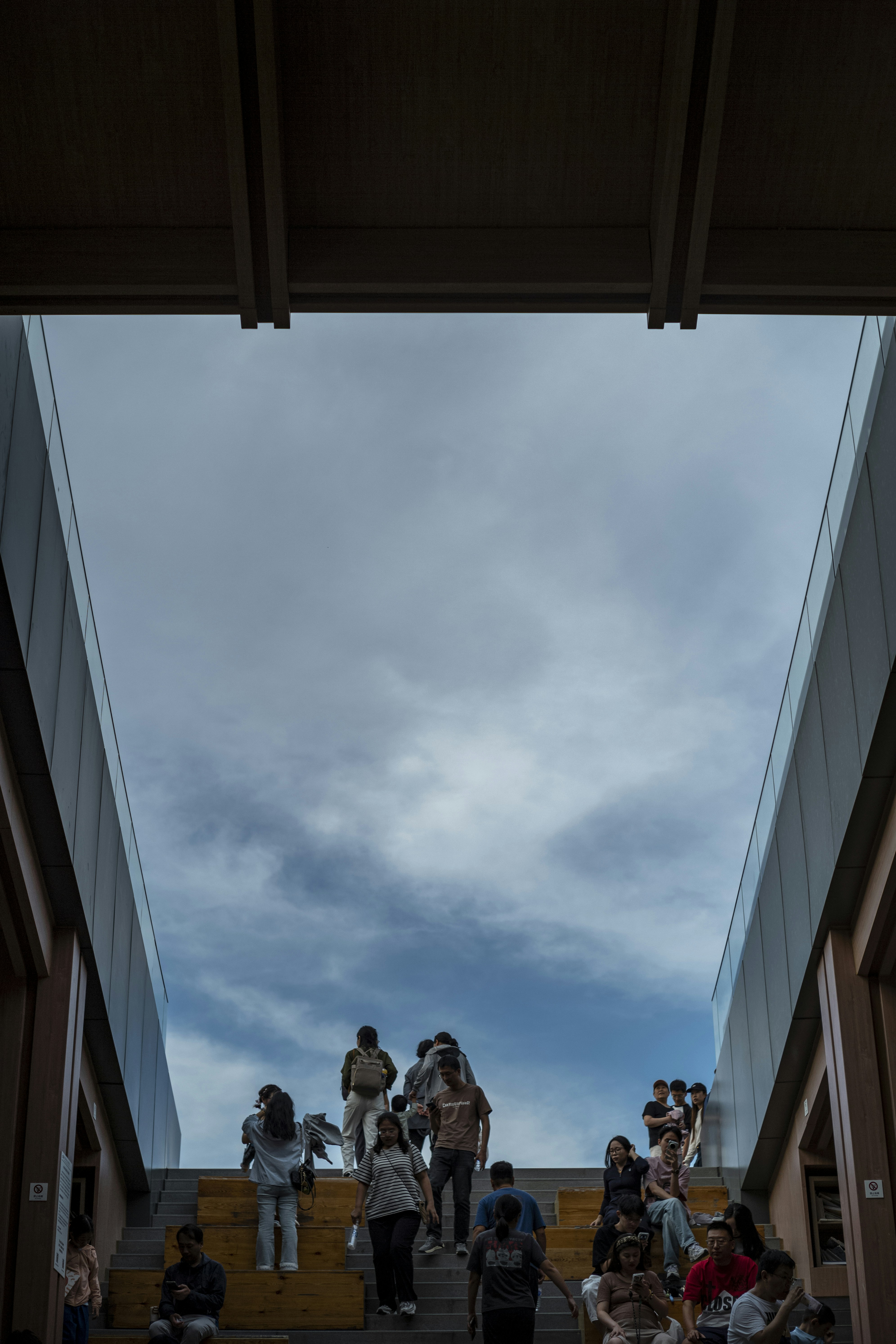 People ascend a wide staircase under a cloudy sky.