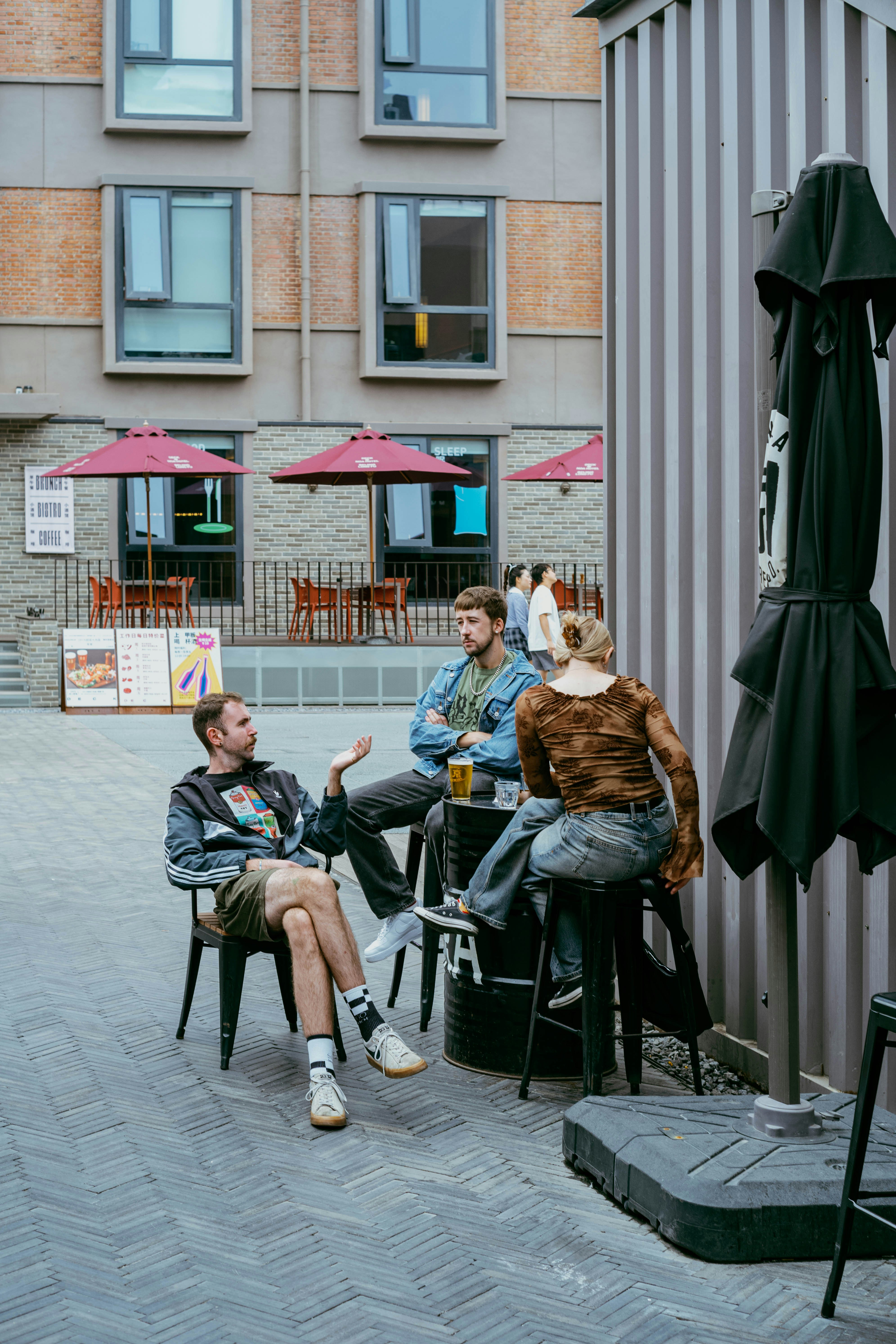 Three friends talking at an outdoor cafe seating area.