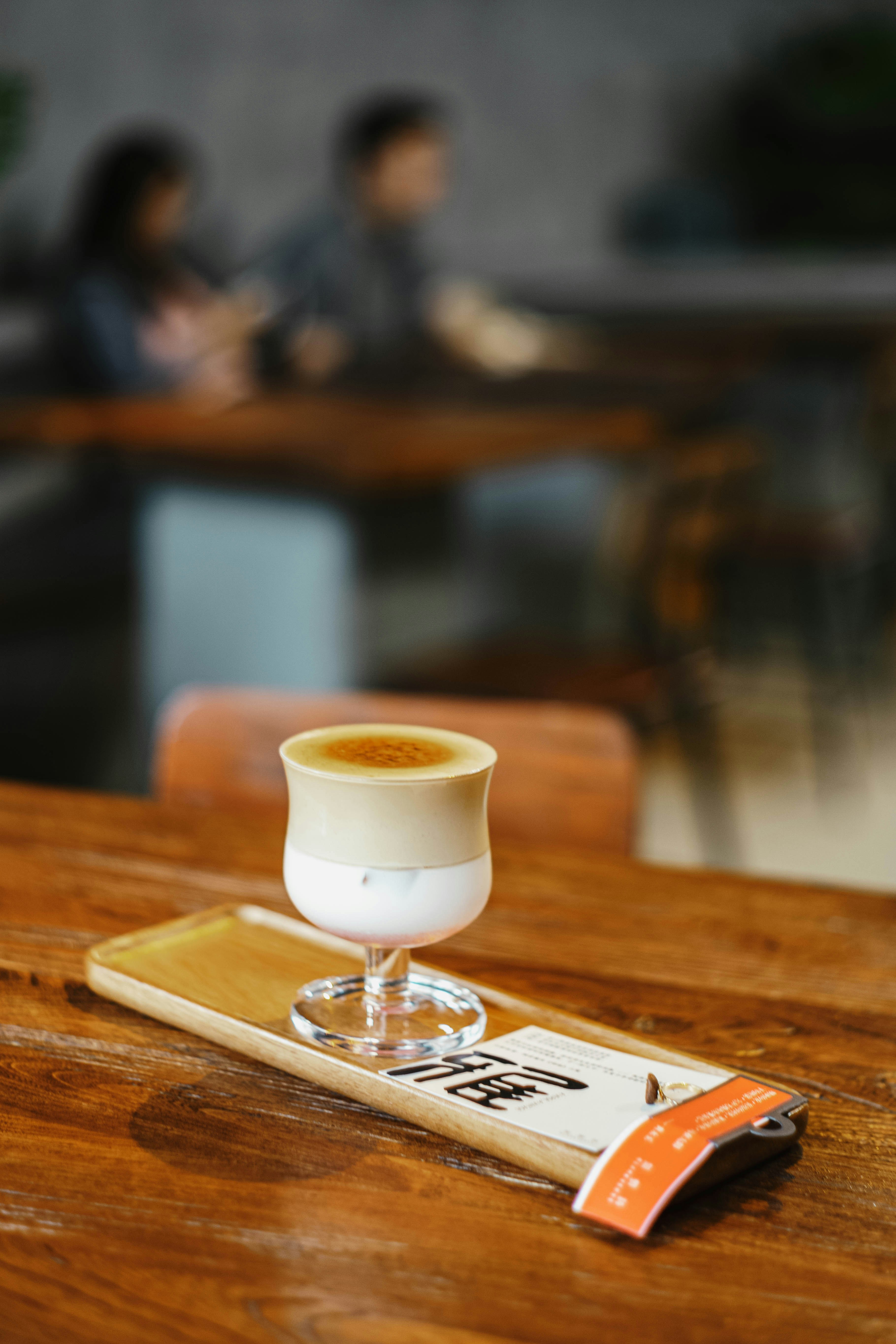 A layered coffee drink on a wooden tray.