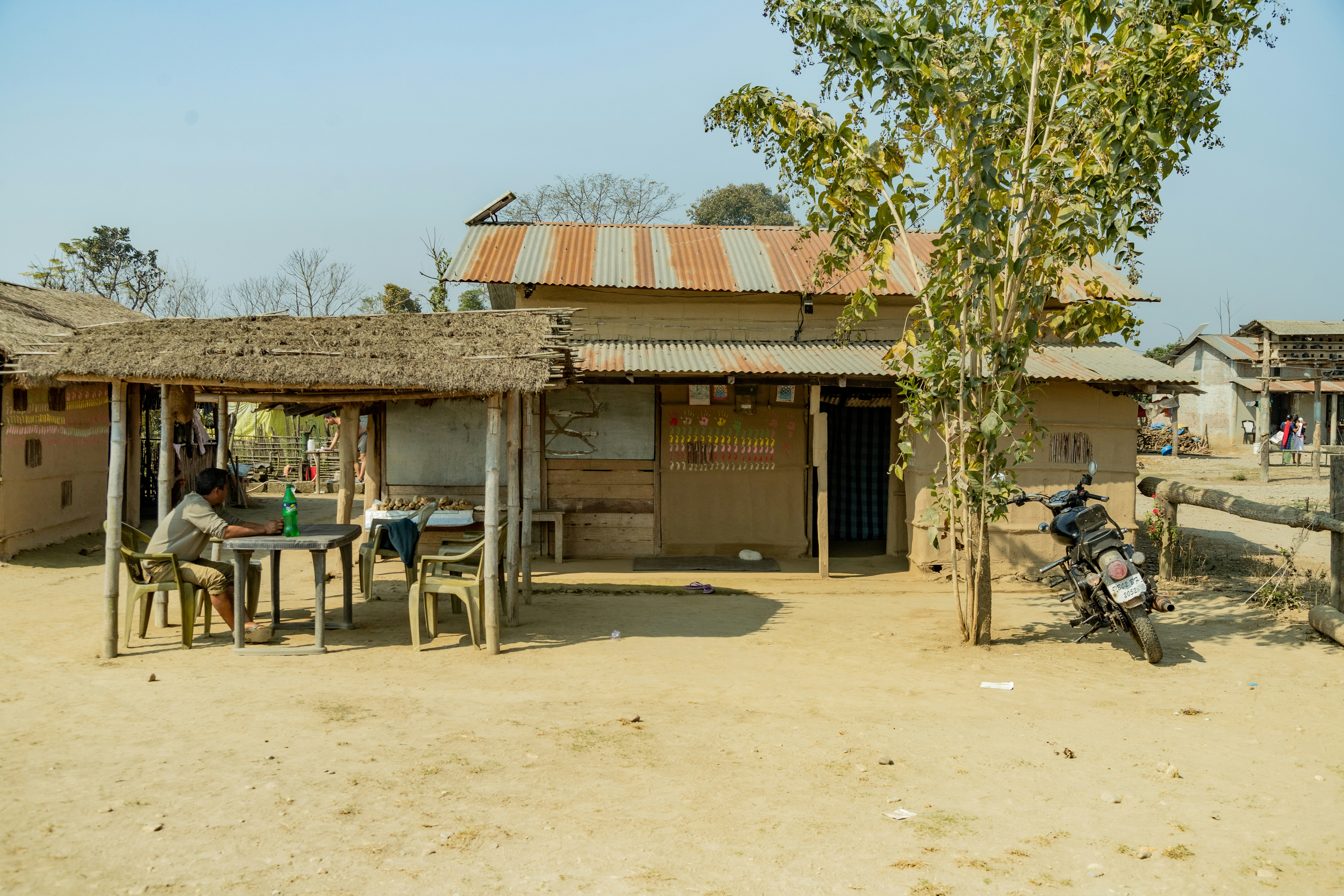 Man sitting at table outside a rural shop