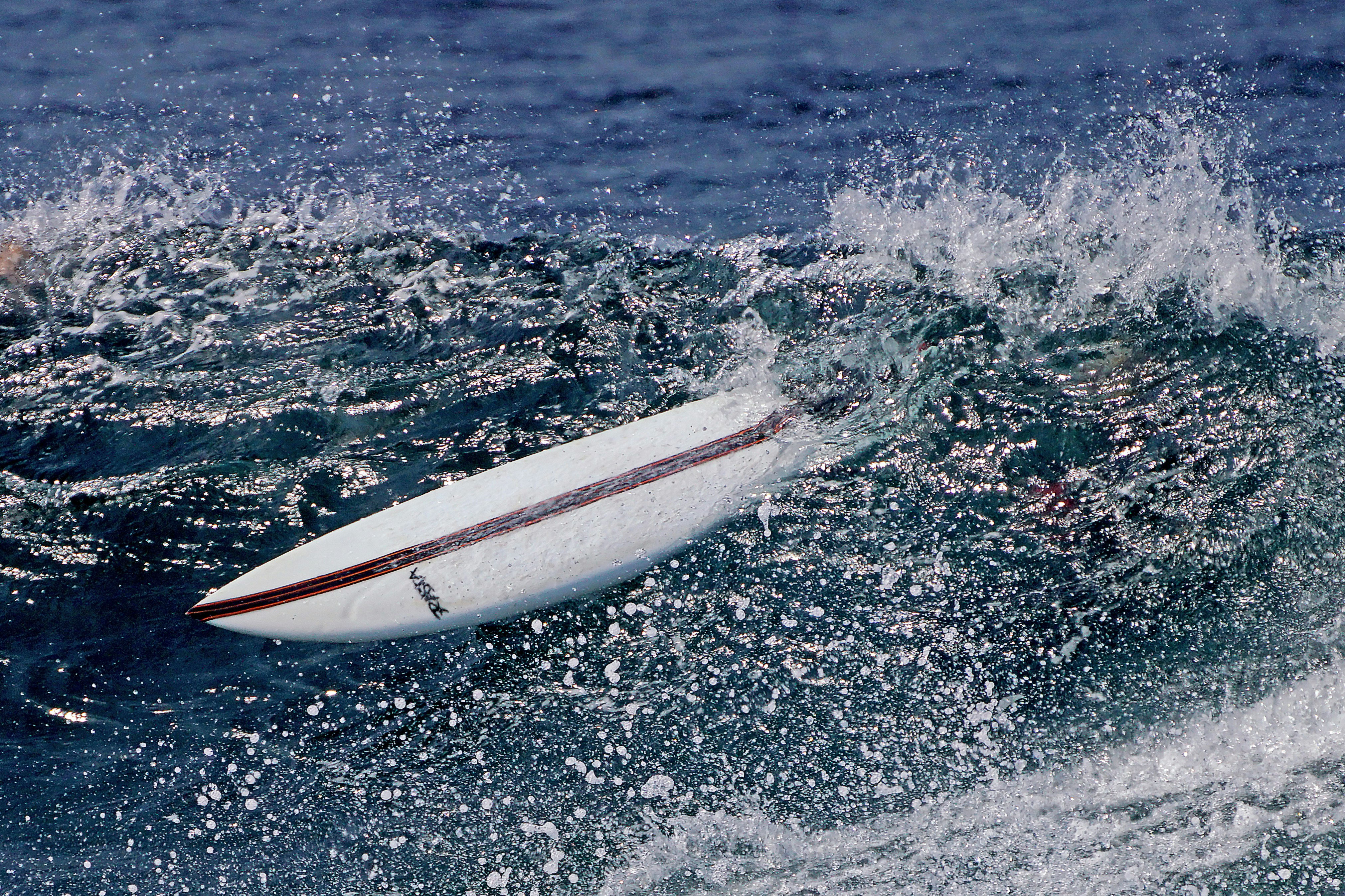 A surfboard rides a breaking ocean wave