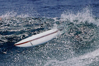 A surfboard rides a breaking ocean wave