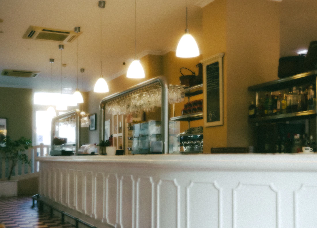 Interior of a bar with a white counter and bottles