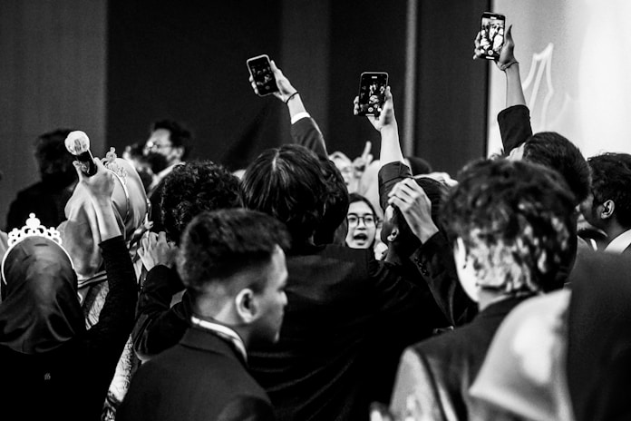 Crowd of people holding up phones recording event