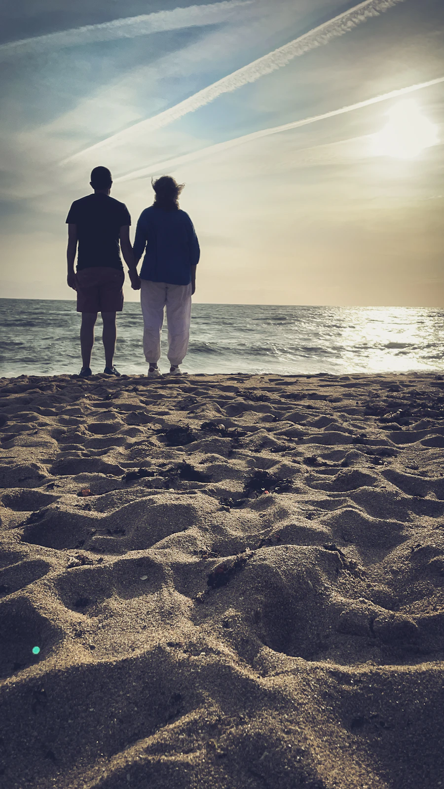 Couple holding hands on a beach at sunset