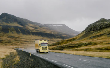 Yellow truck driving on a winding road through mountains