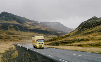 Yellow truck driving on a winding road through mountains