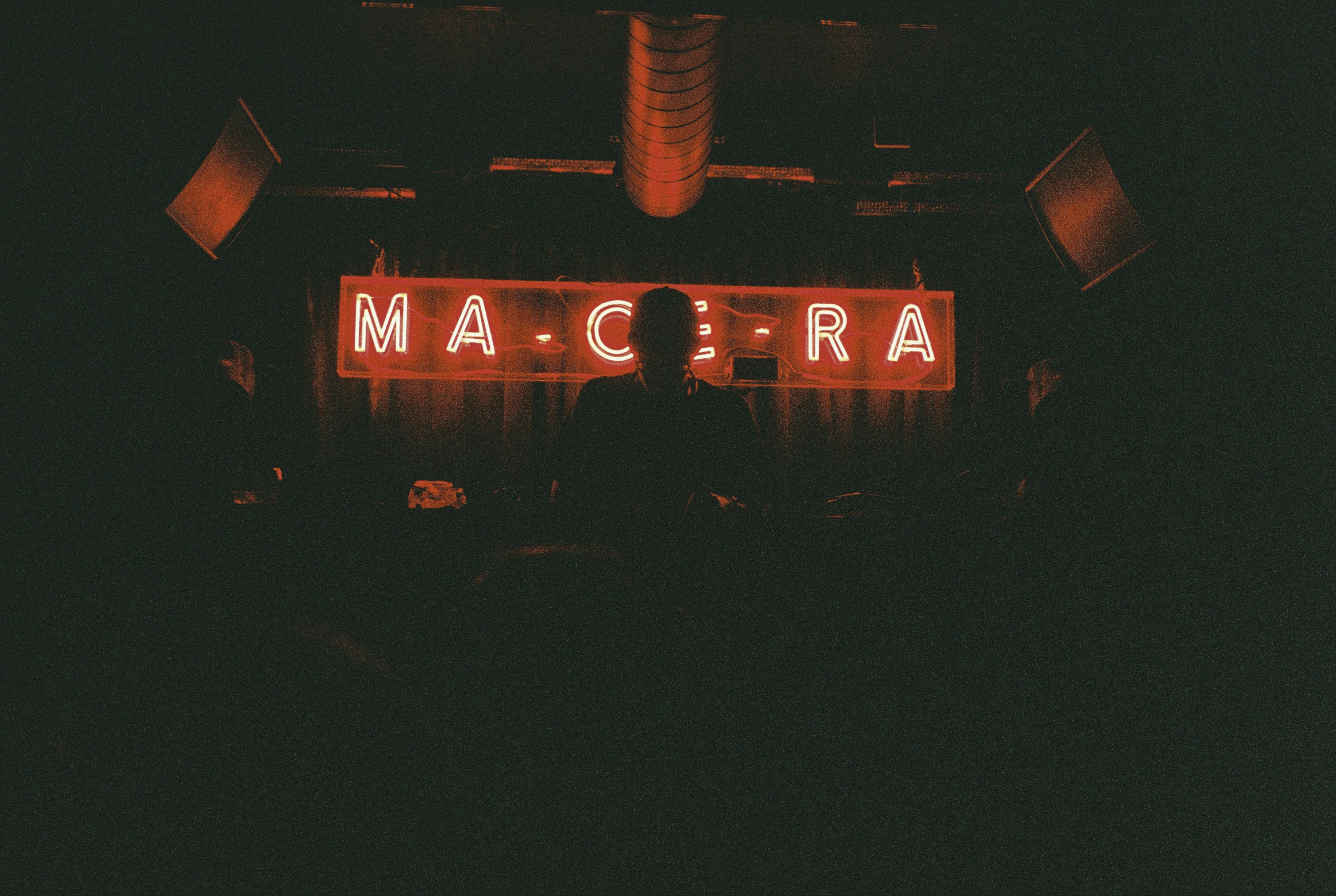 DJ performing in front of neon sign at night