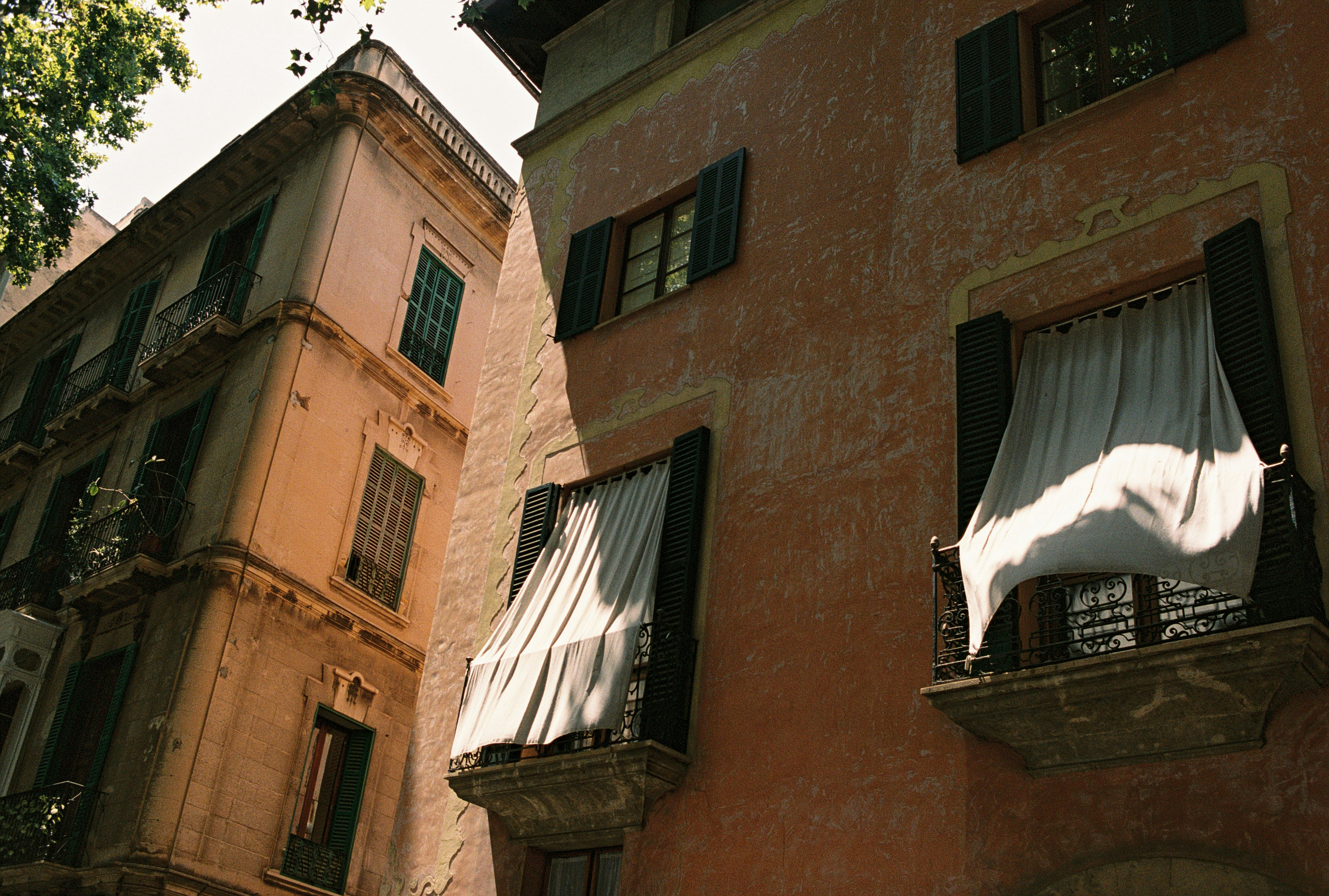 Curtains blow gently from balconies on old buildings.