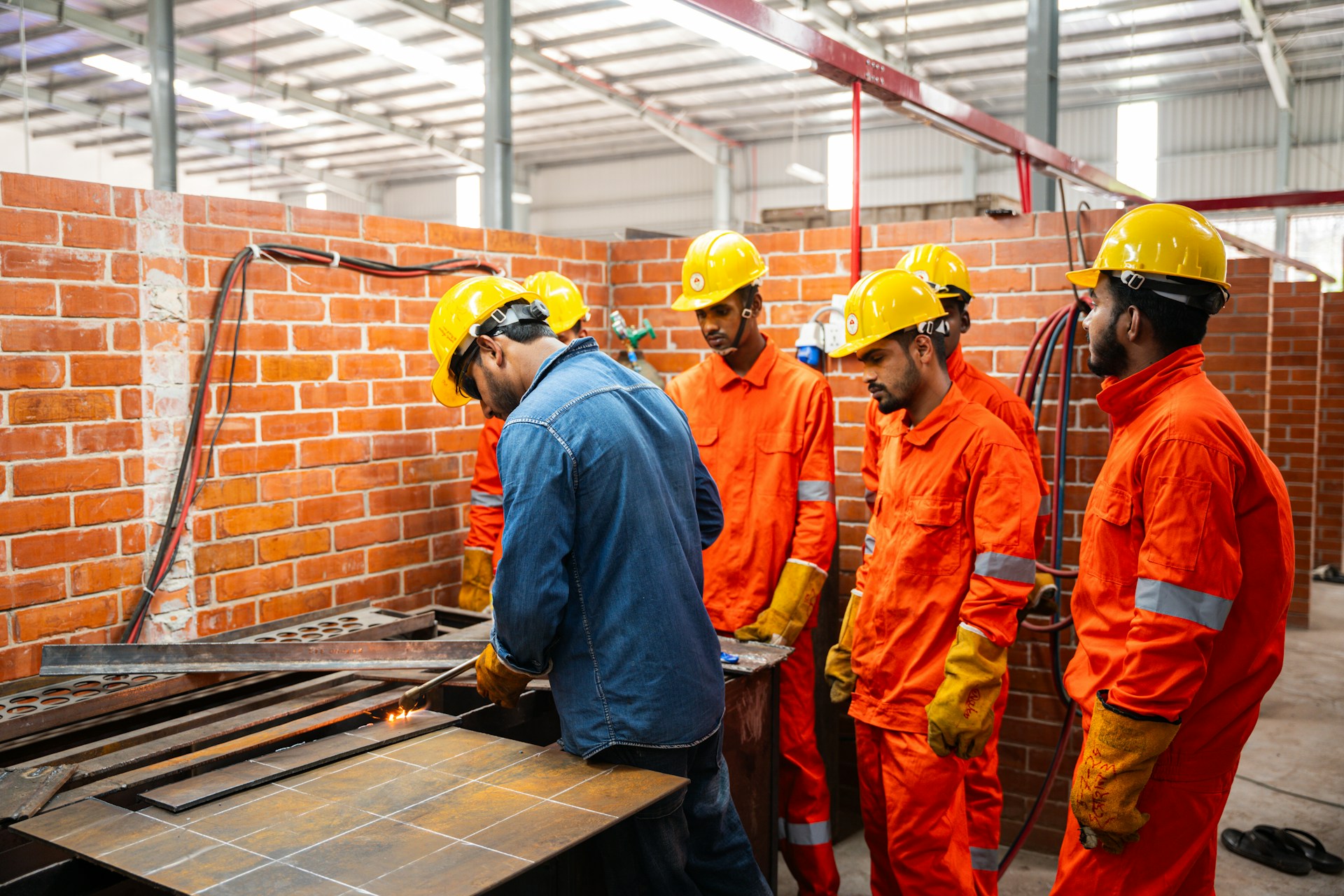 Workers in hard hats and safety vests in a workshop