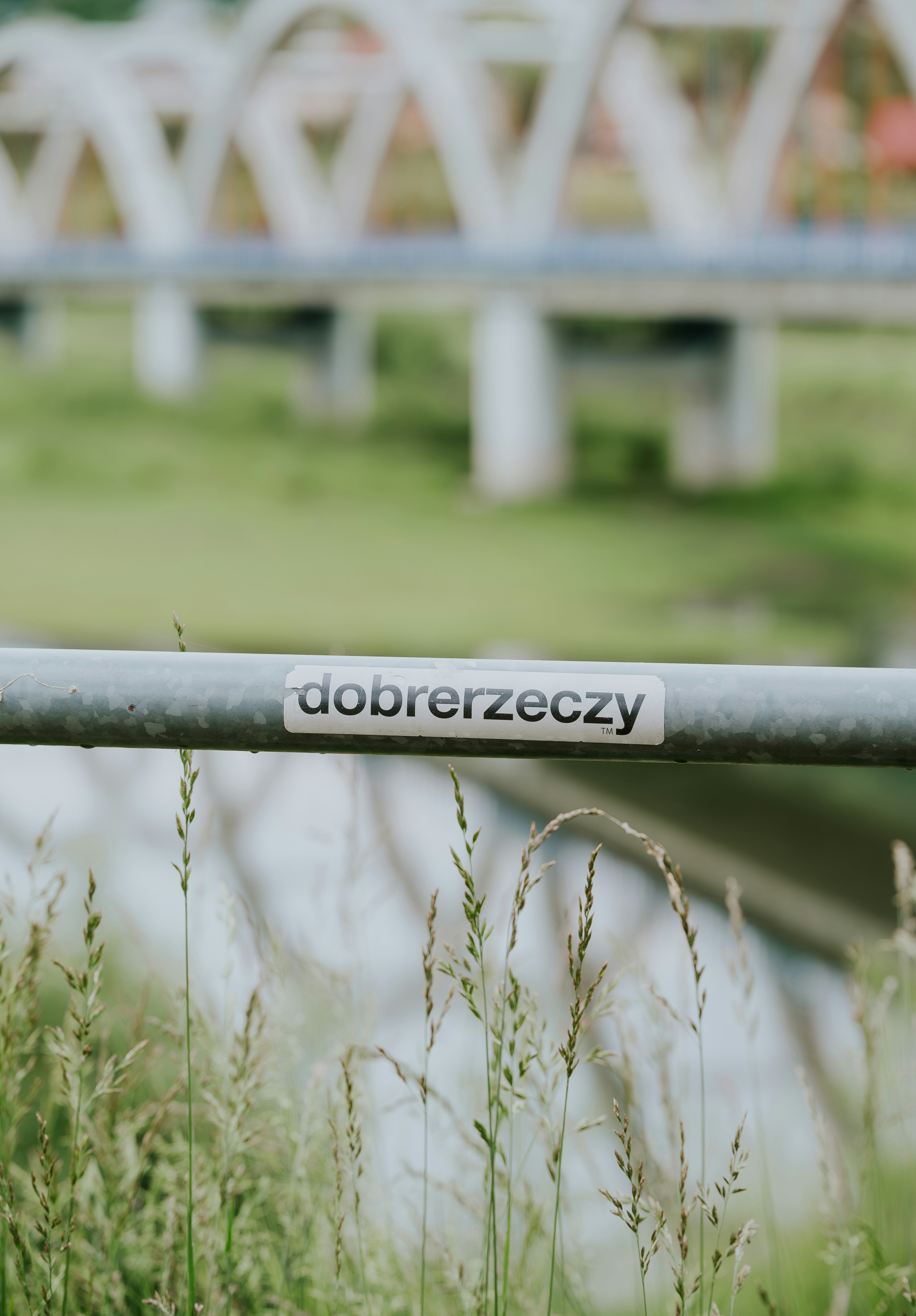 Metal railing with 'dobrezeczy' label and bridge background.