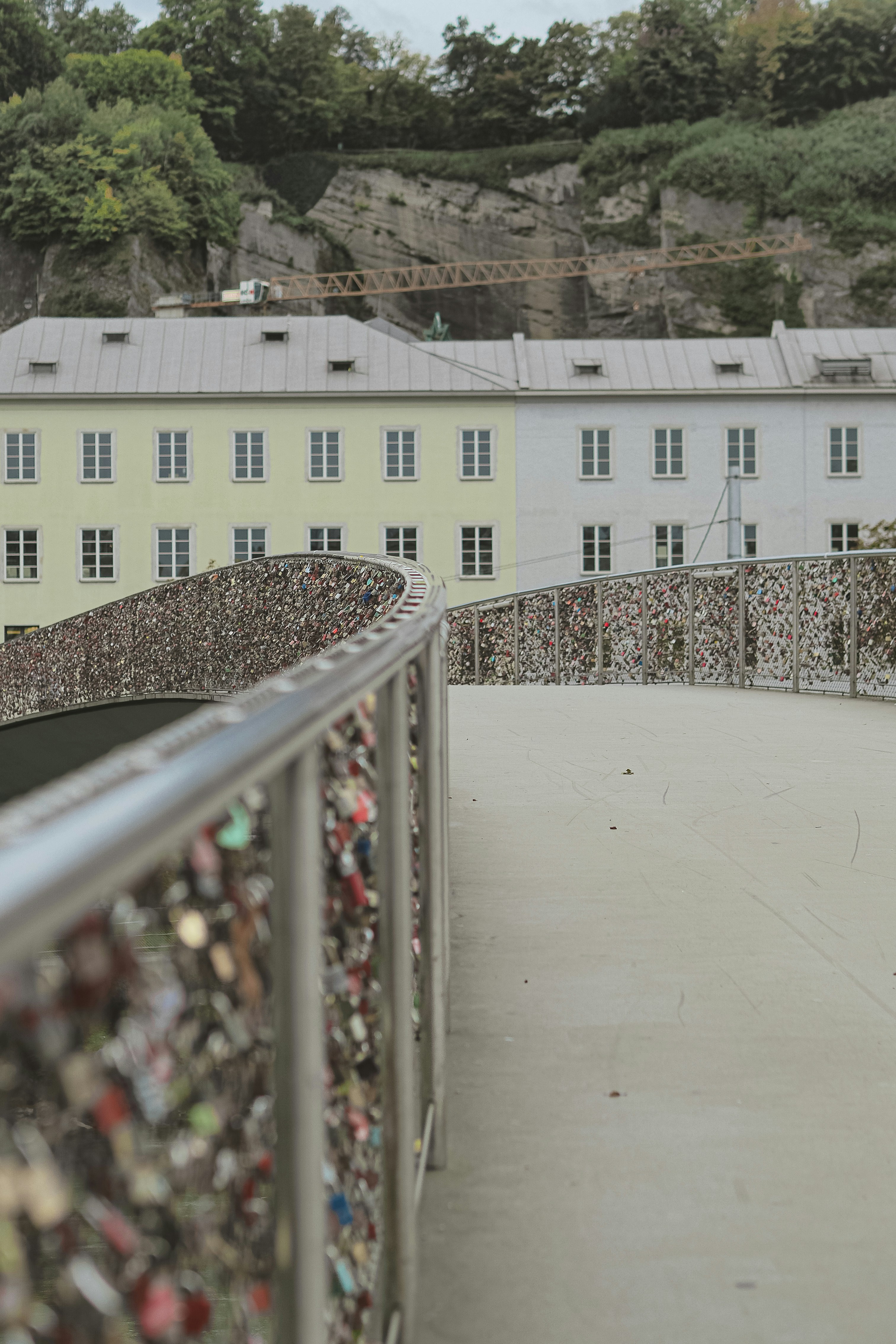 Bridge railing covered in love locks with buildings behind.