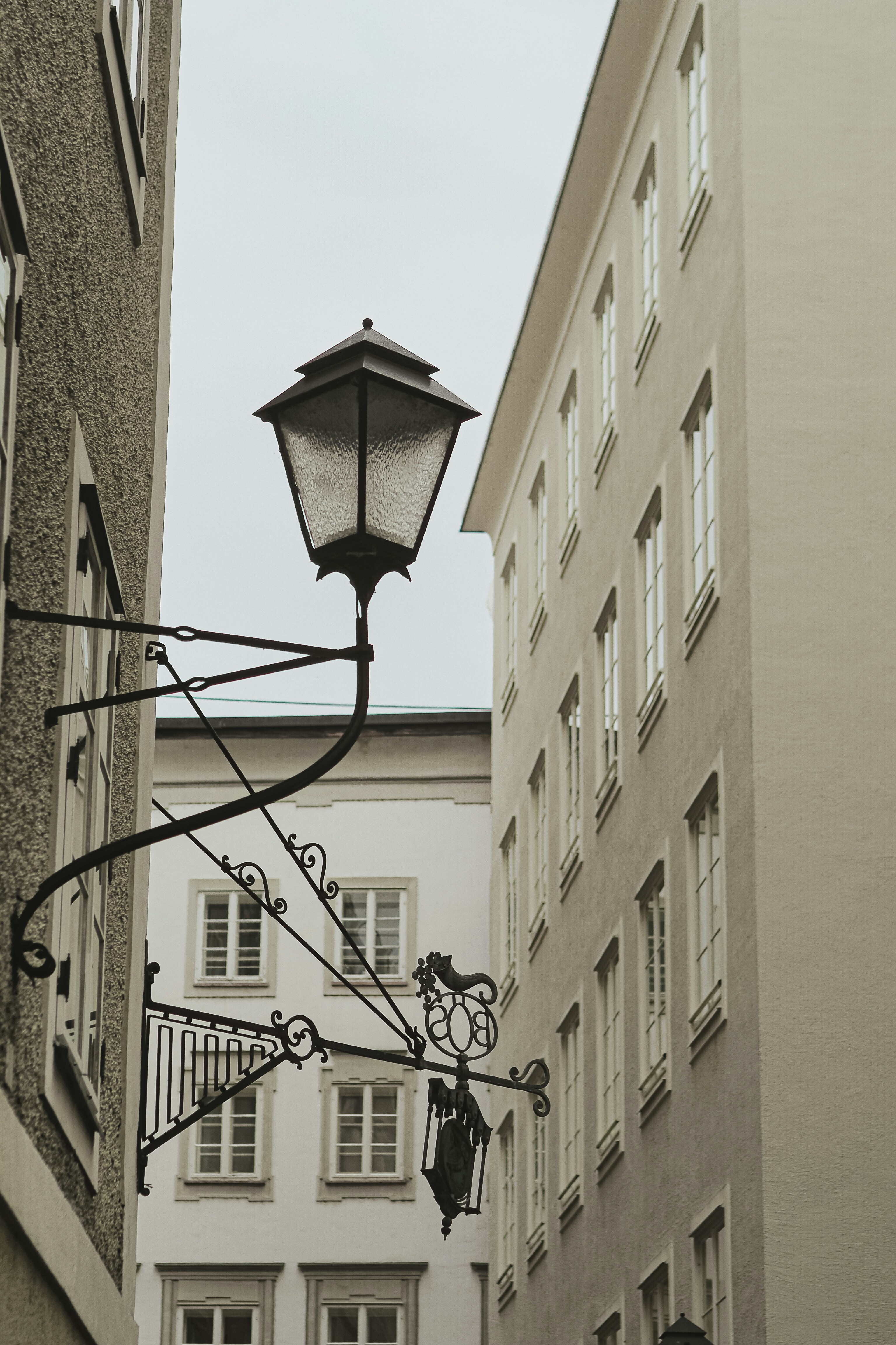 Old street lamp on building facade with windows.