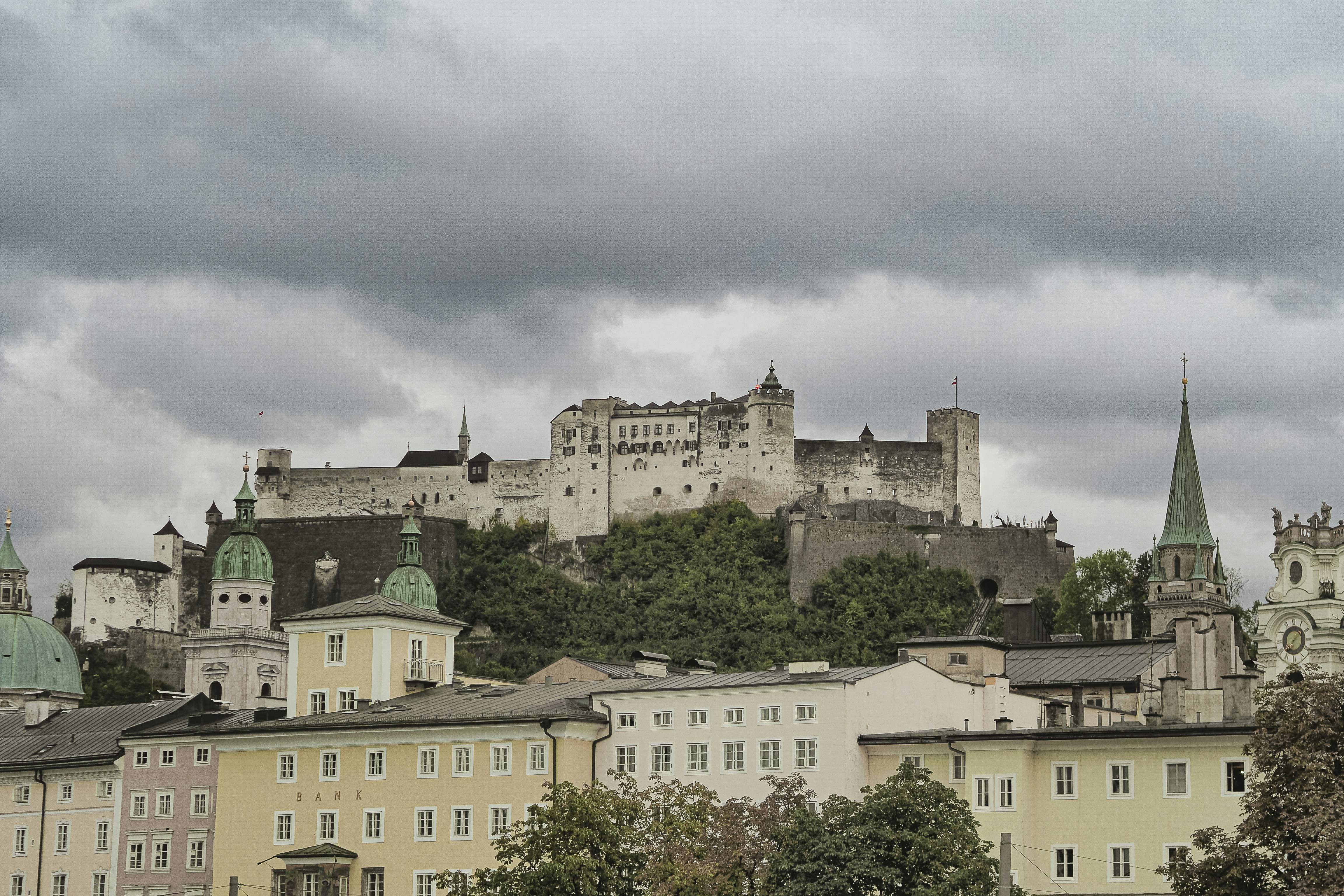 Hohensalzburg fortress overlooking colorful buildings under cloudy sky