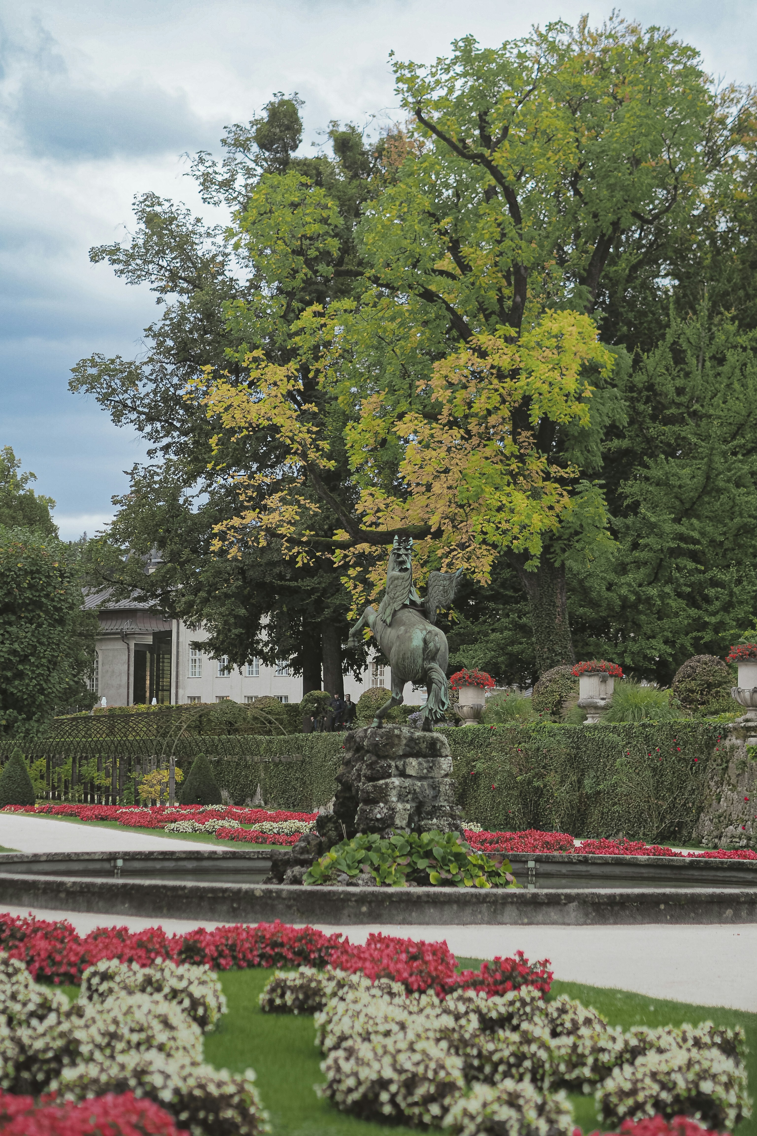 Sculpture in a formal garden with colorful flowers