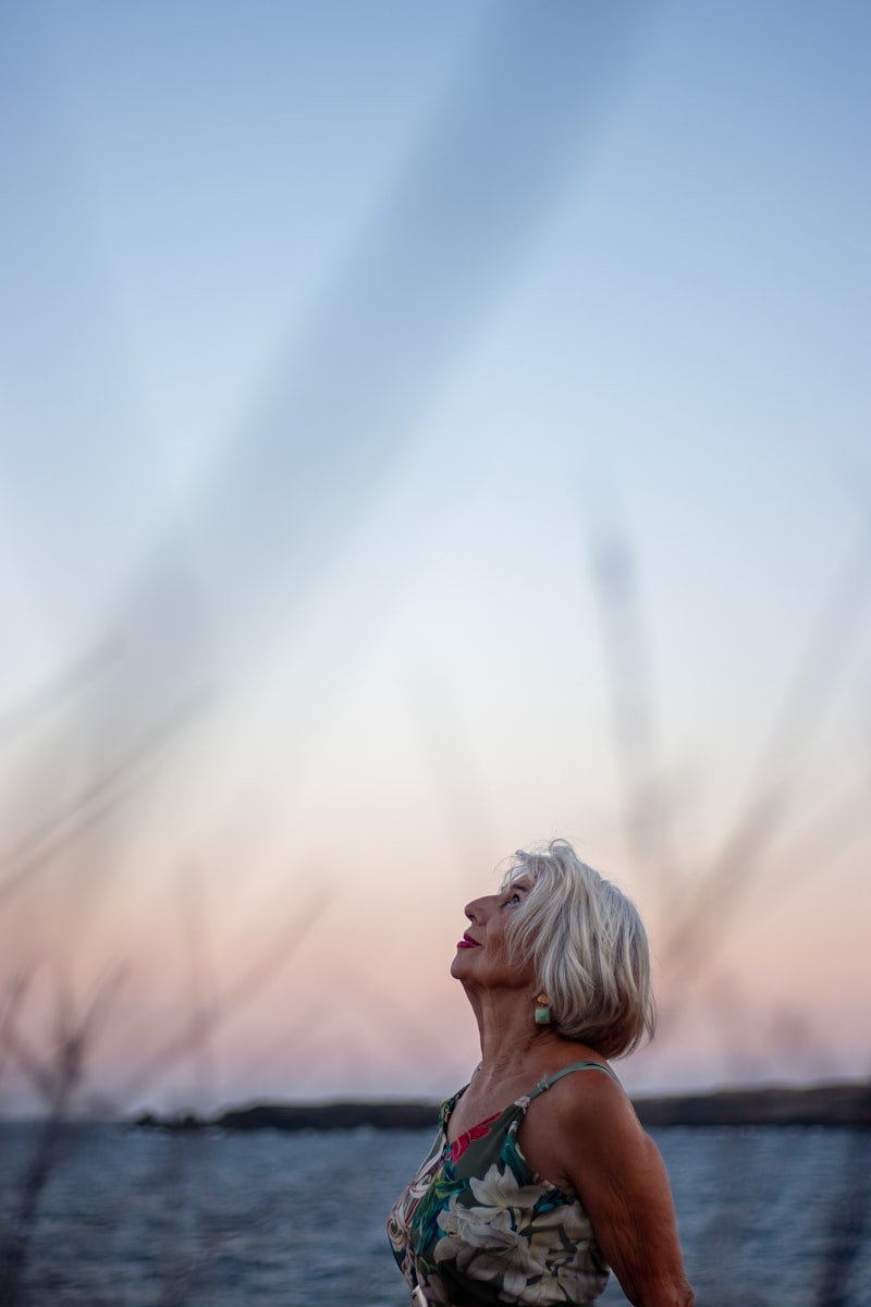 Senior woman looking peacefully at the sky at sunset, reflecting on life after loss
