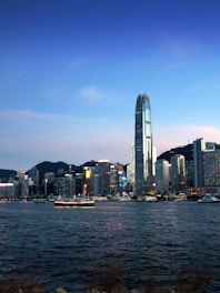 Modern cityscape with skyscrapers and a boat on water.