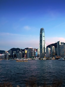Modern cityscape with skyscrapers and a boat on water.