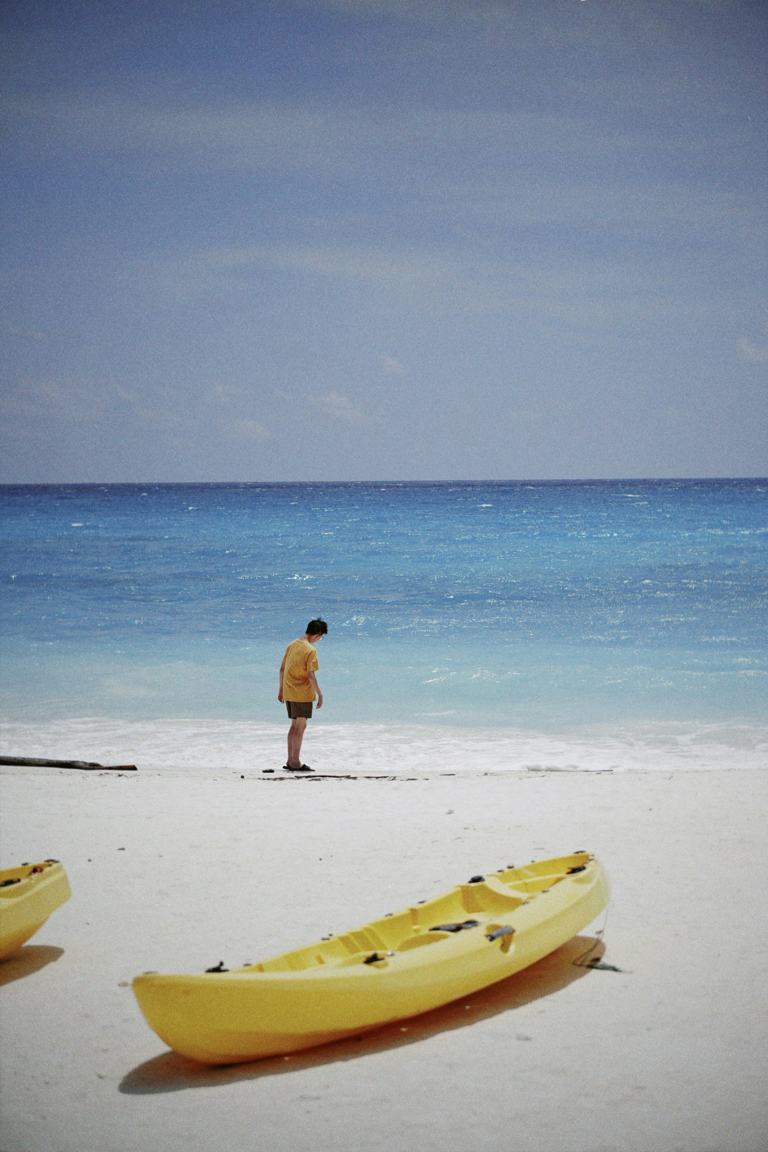 Man standing on a beach with yellow kayaks