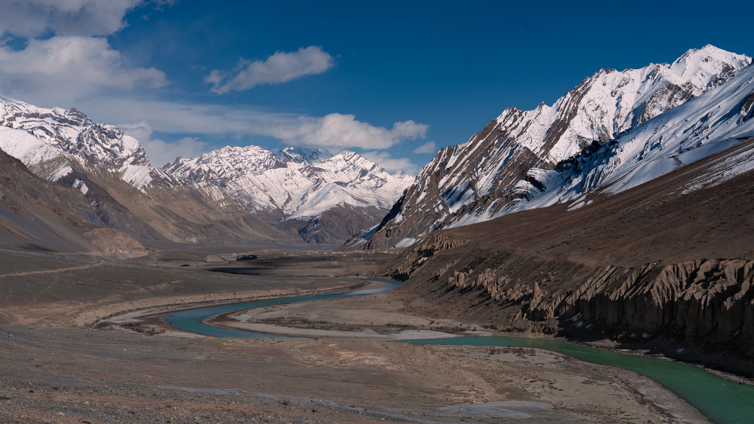 A winding river below snow-capped Himalayan peaks