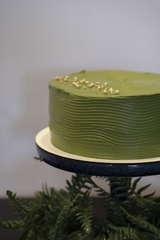 Green cake with ripple frosting and gold pearls.