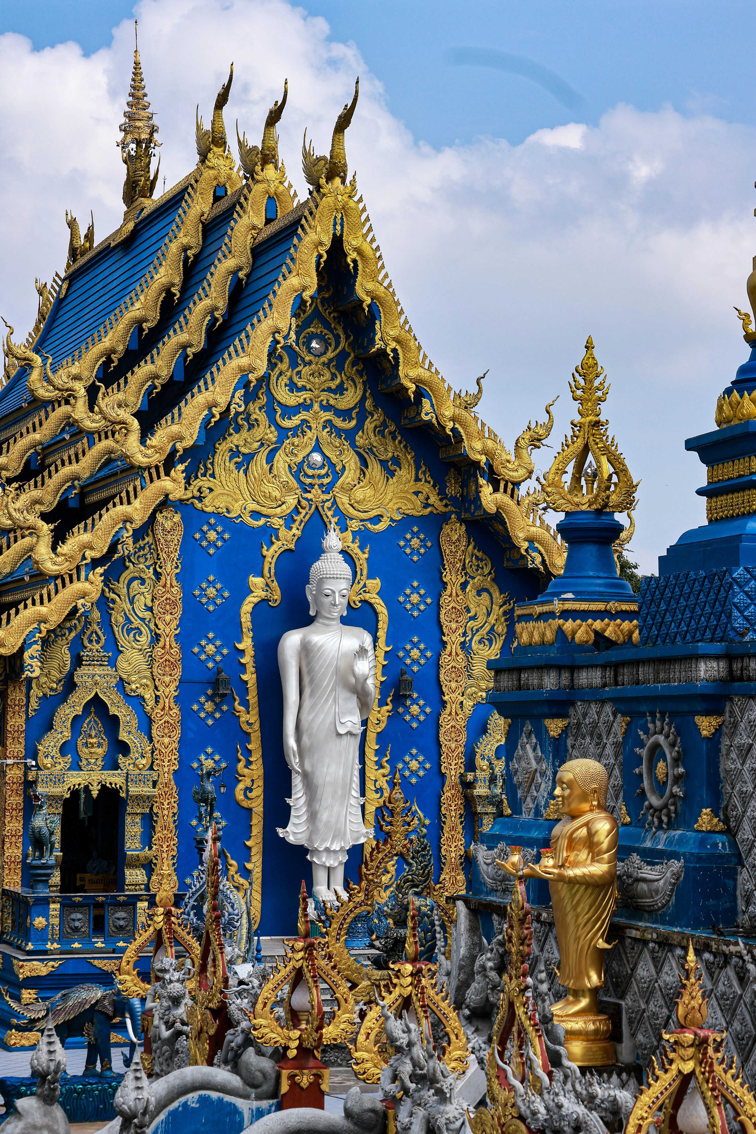Blaue Fassade mit Goldornamenten und weißer Buddhafigur am Wat Rong Suea Ten in Chiang Rai