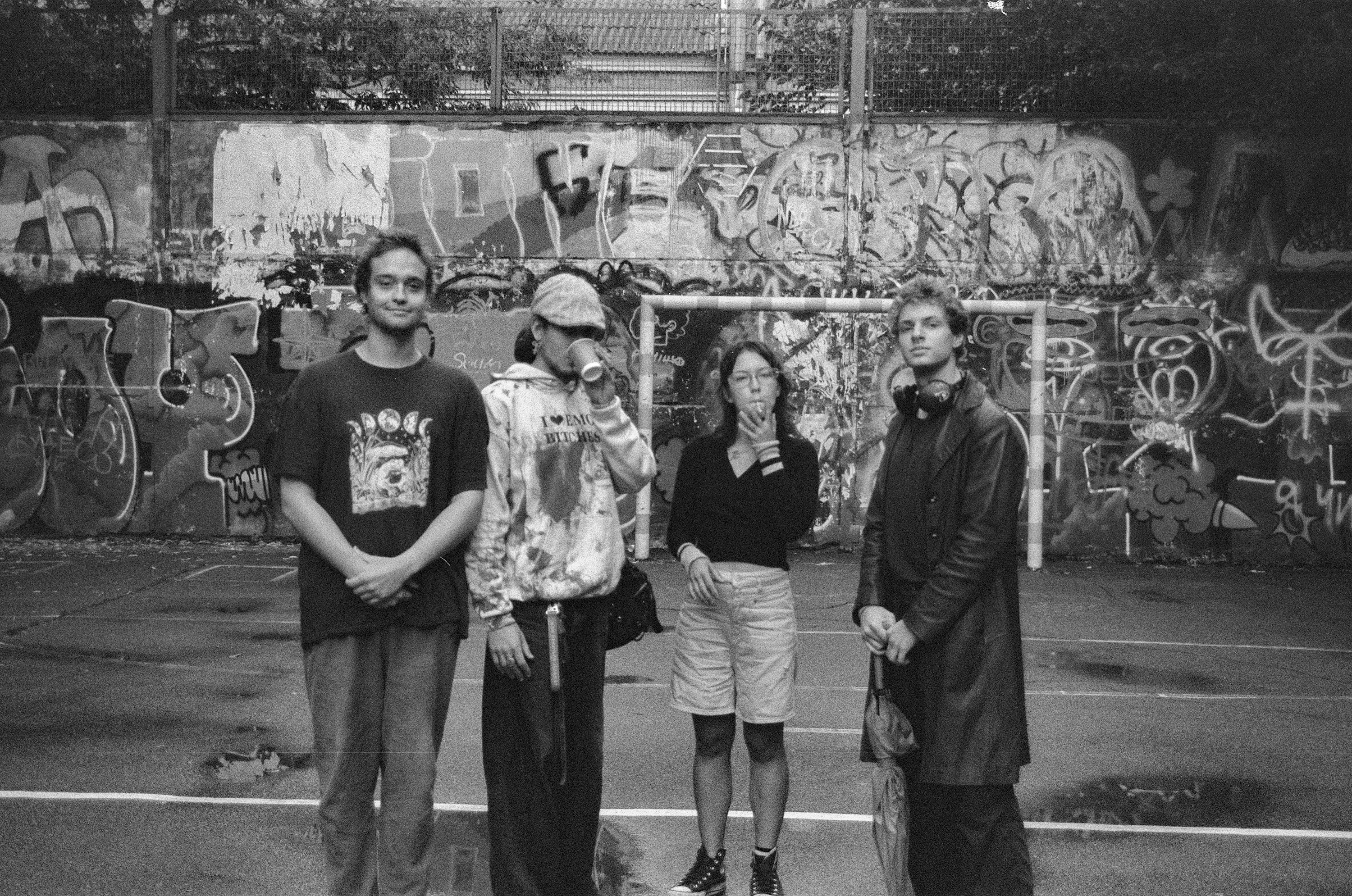 Four people stand in front of graffiti wall