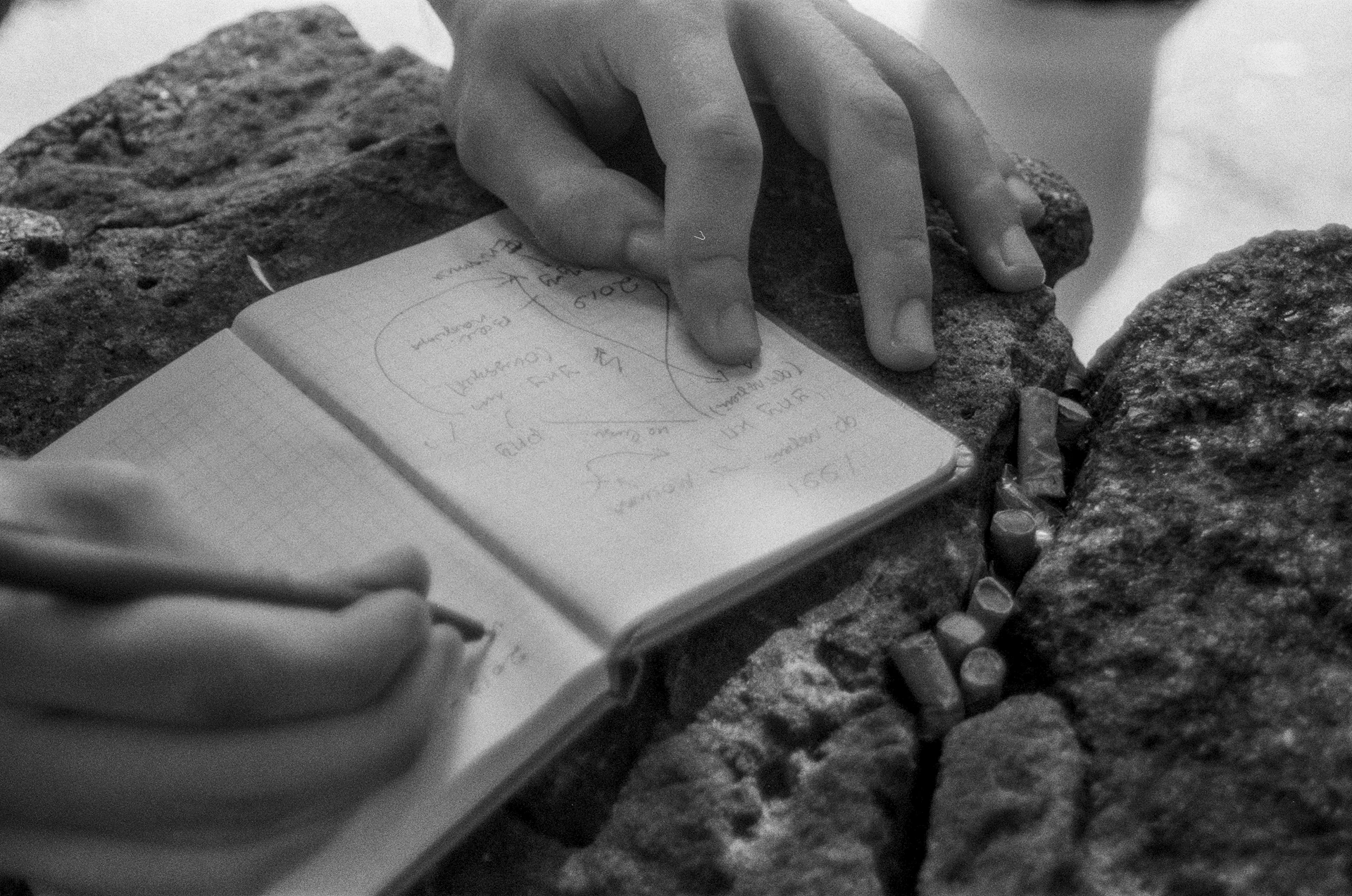 Hands pointing at sketches in an open notebook.