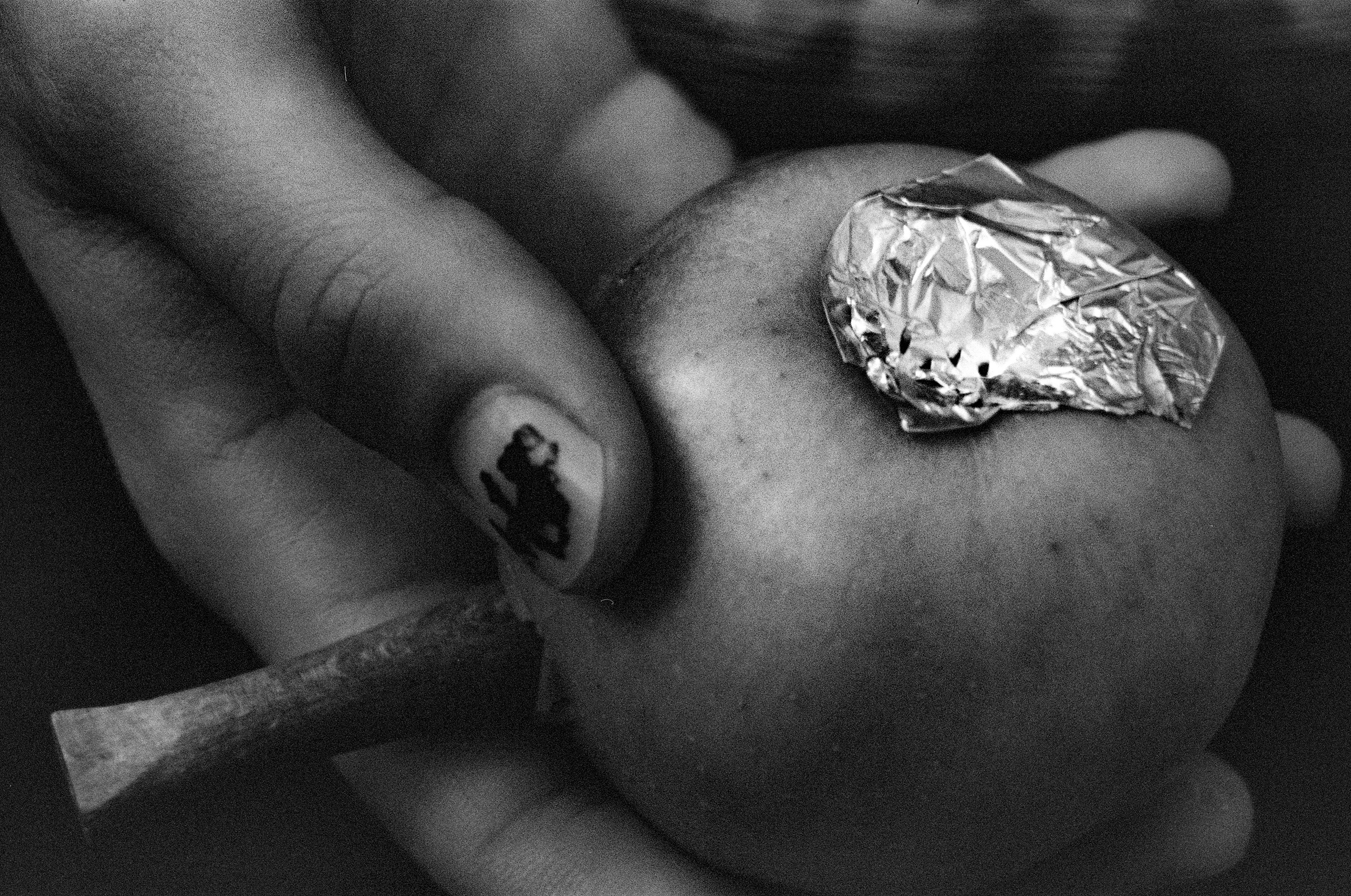 Hands holding an apple with foil on top.