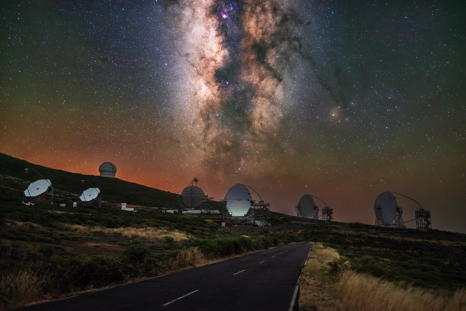 Cupole di osservatorio sotto la via lattea, strada buia in primo piano