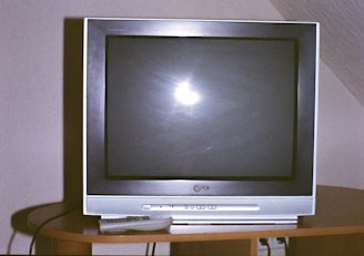 A television set with a remote control on a table.