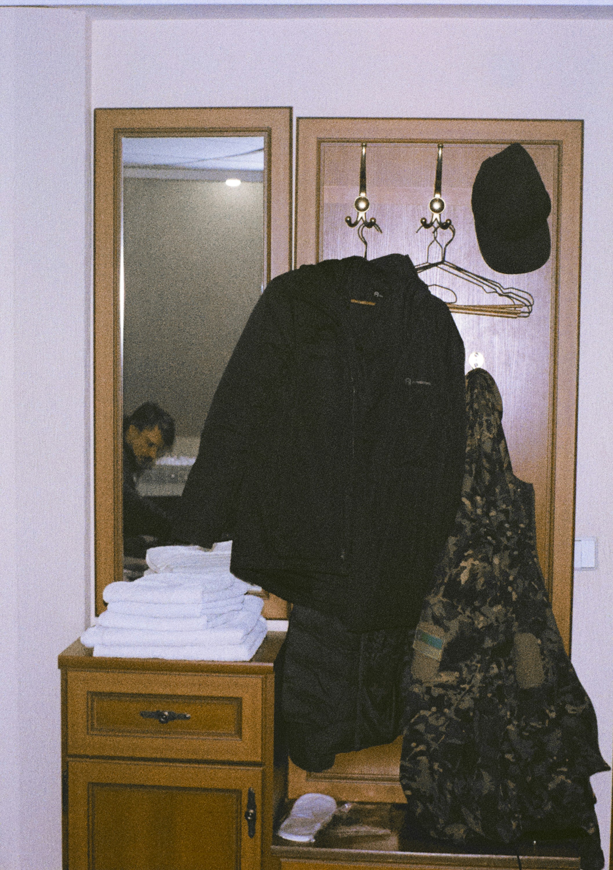 Coat, cap, and towels on entryway furniture.