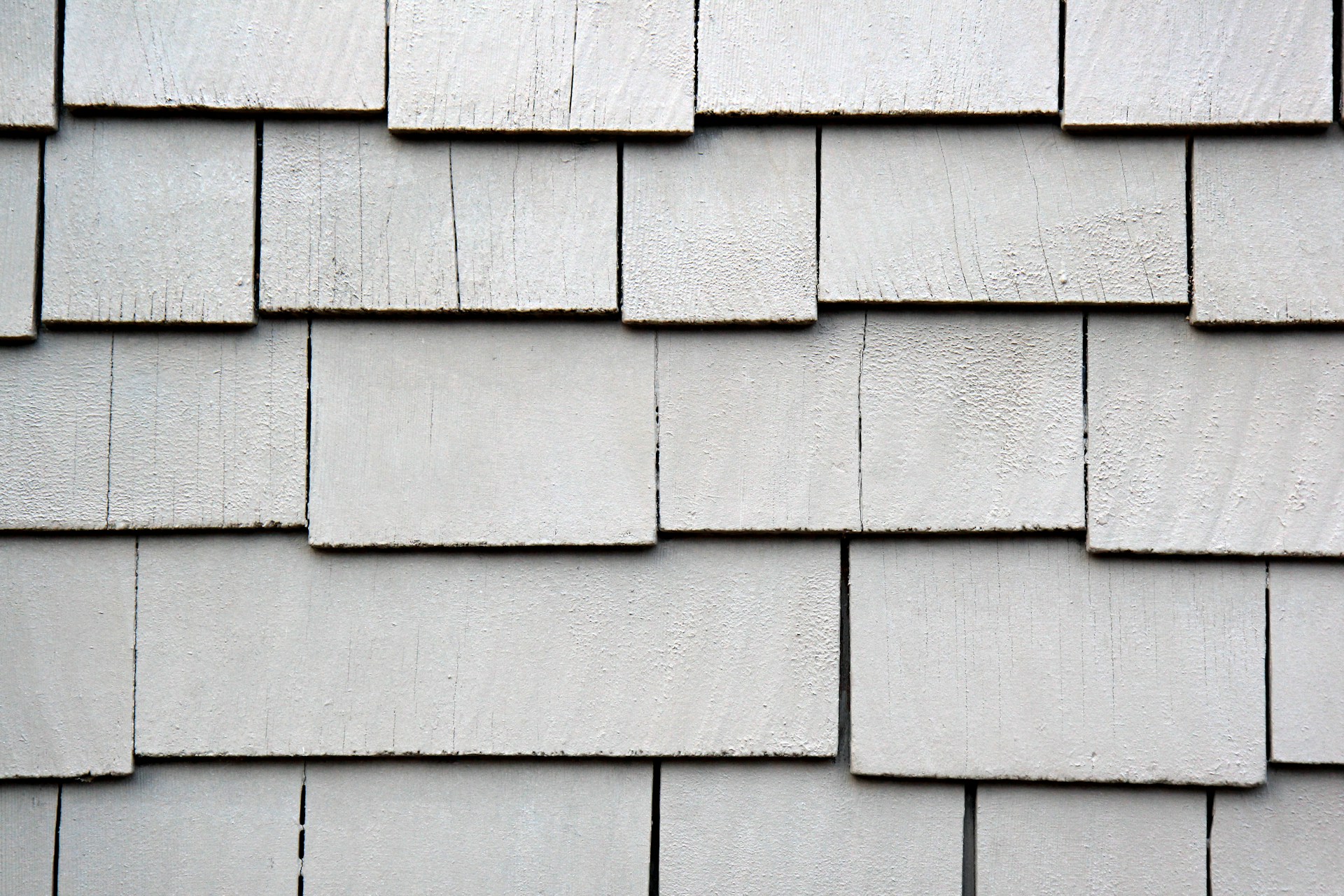 Close-up of weathered grey wooden shingles on a wall.