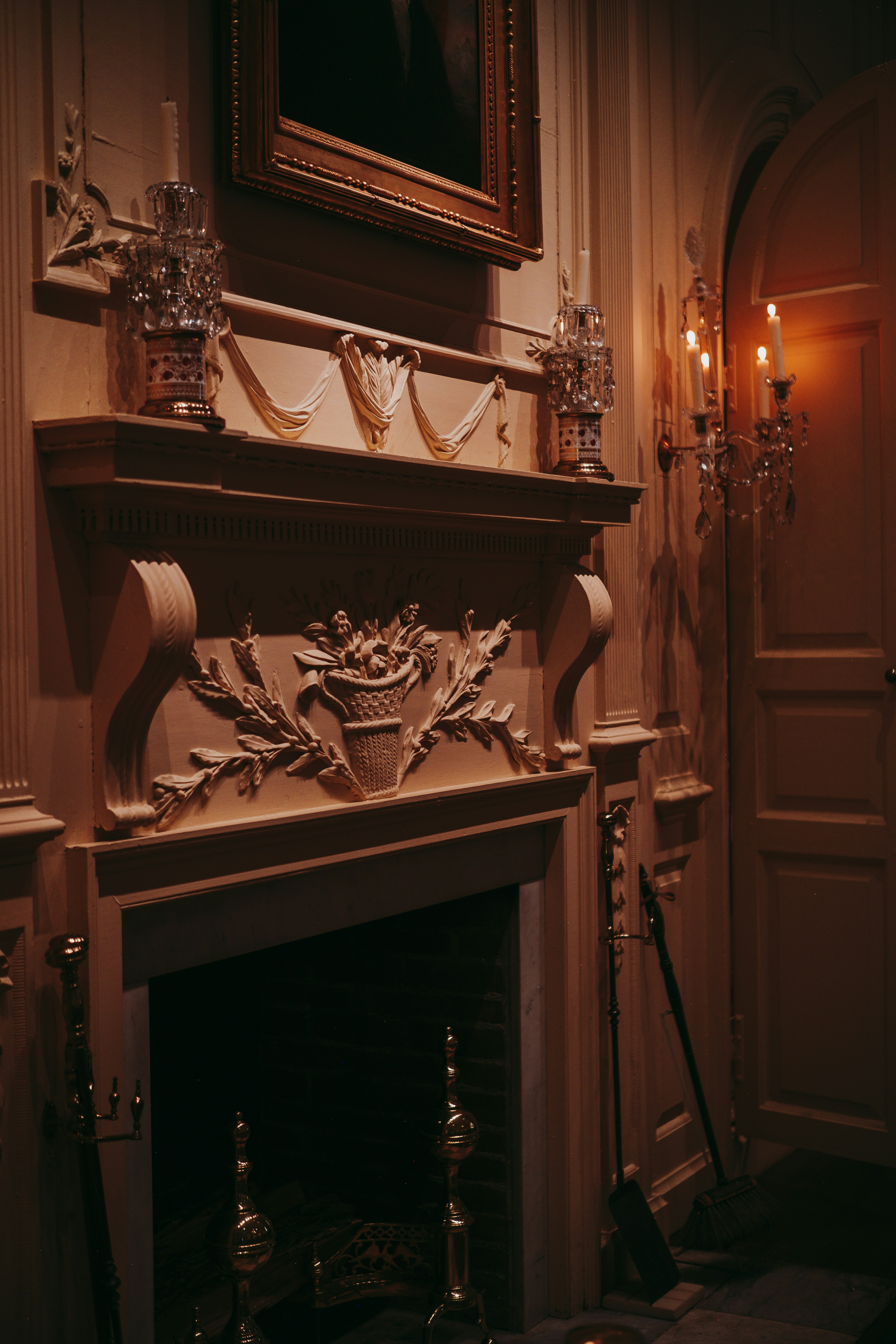 Ornate fireplace with decorative carvings and a painting.