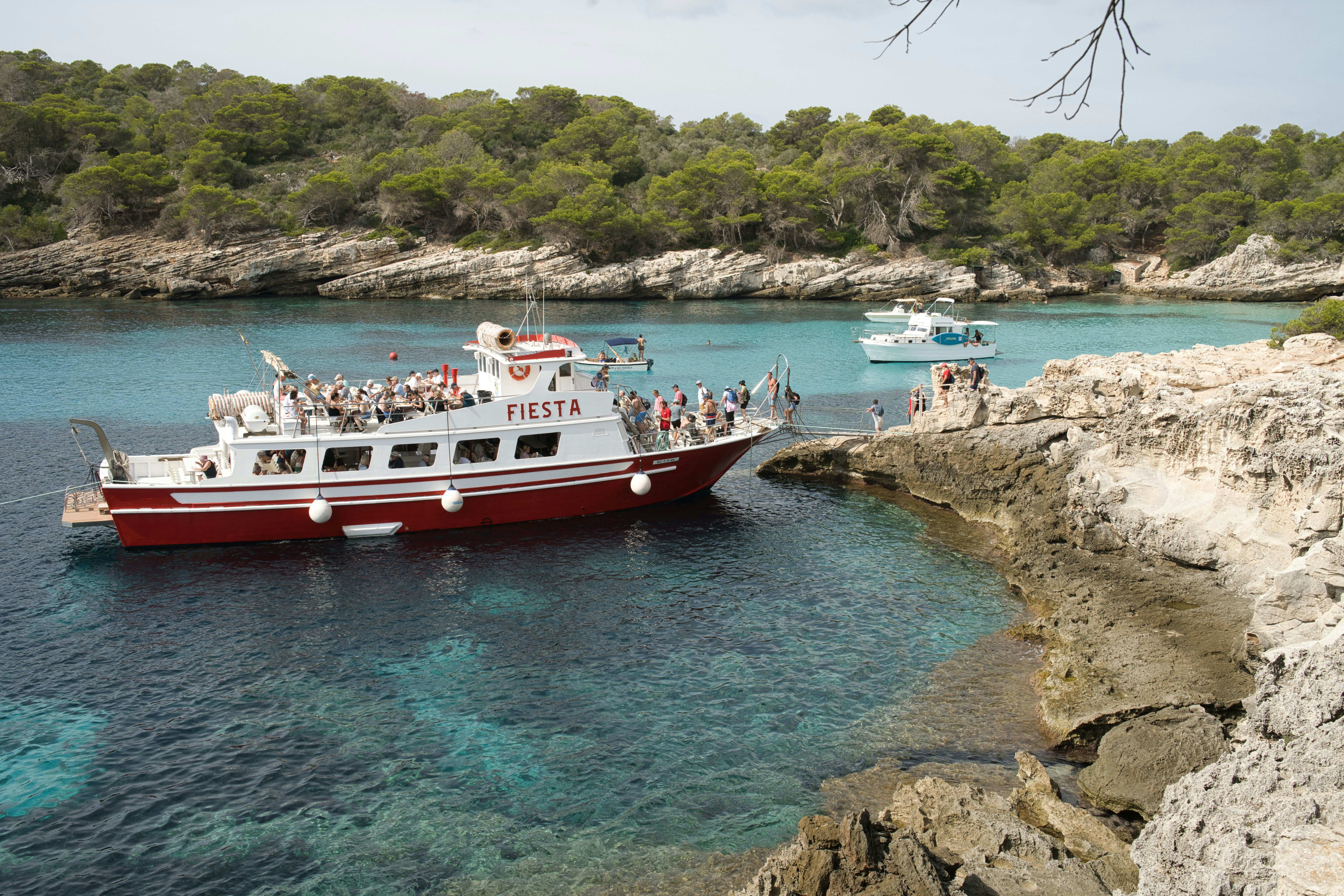 Tour boat filled with people in a clear blue bay.
