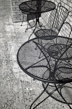 Two empty metal tables and chairs outside.