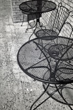 Two empty metal tables and chairs outside.