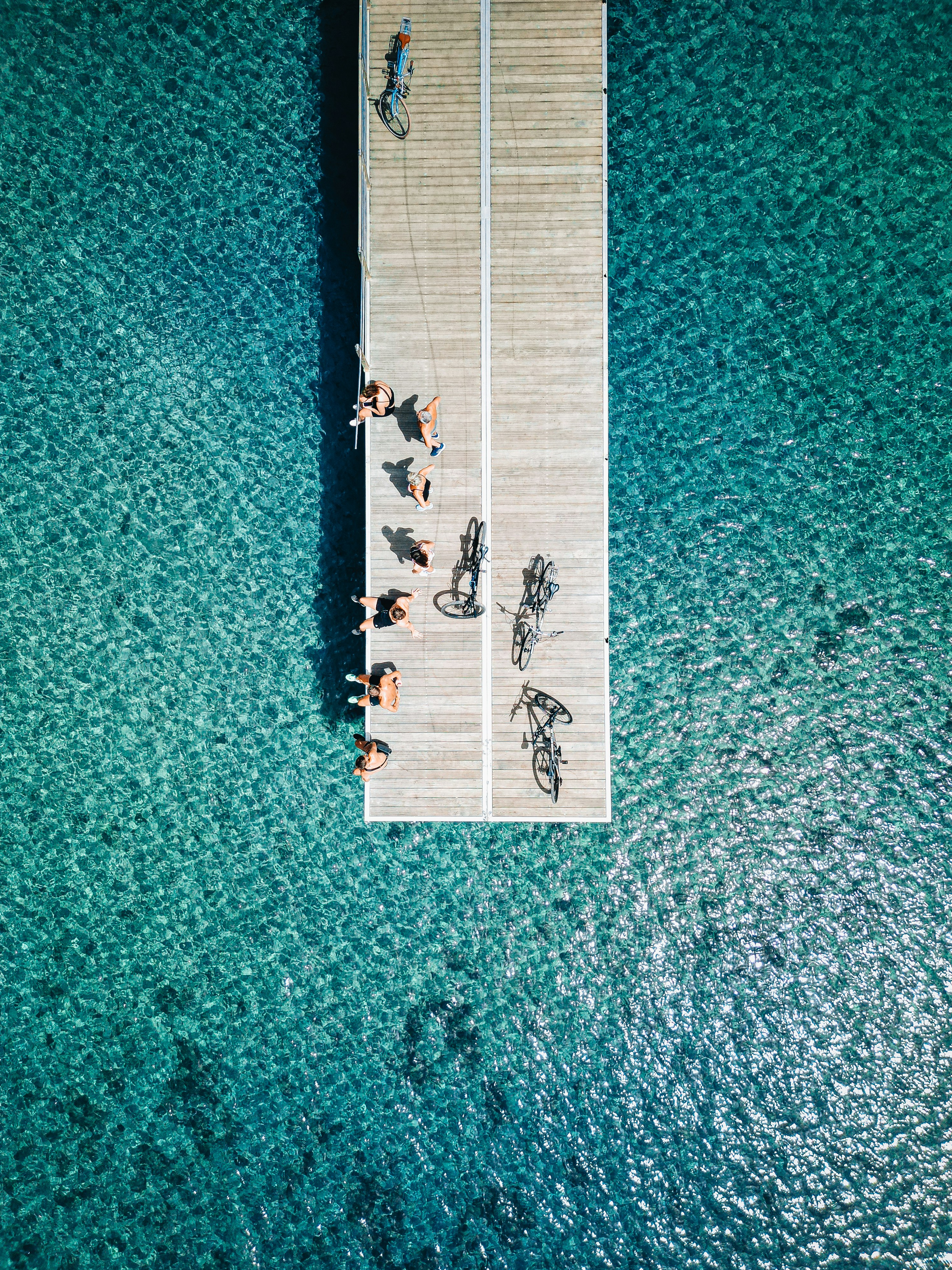 People and bicycles on a wooden pier over clear water