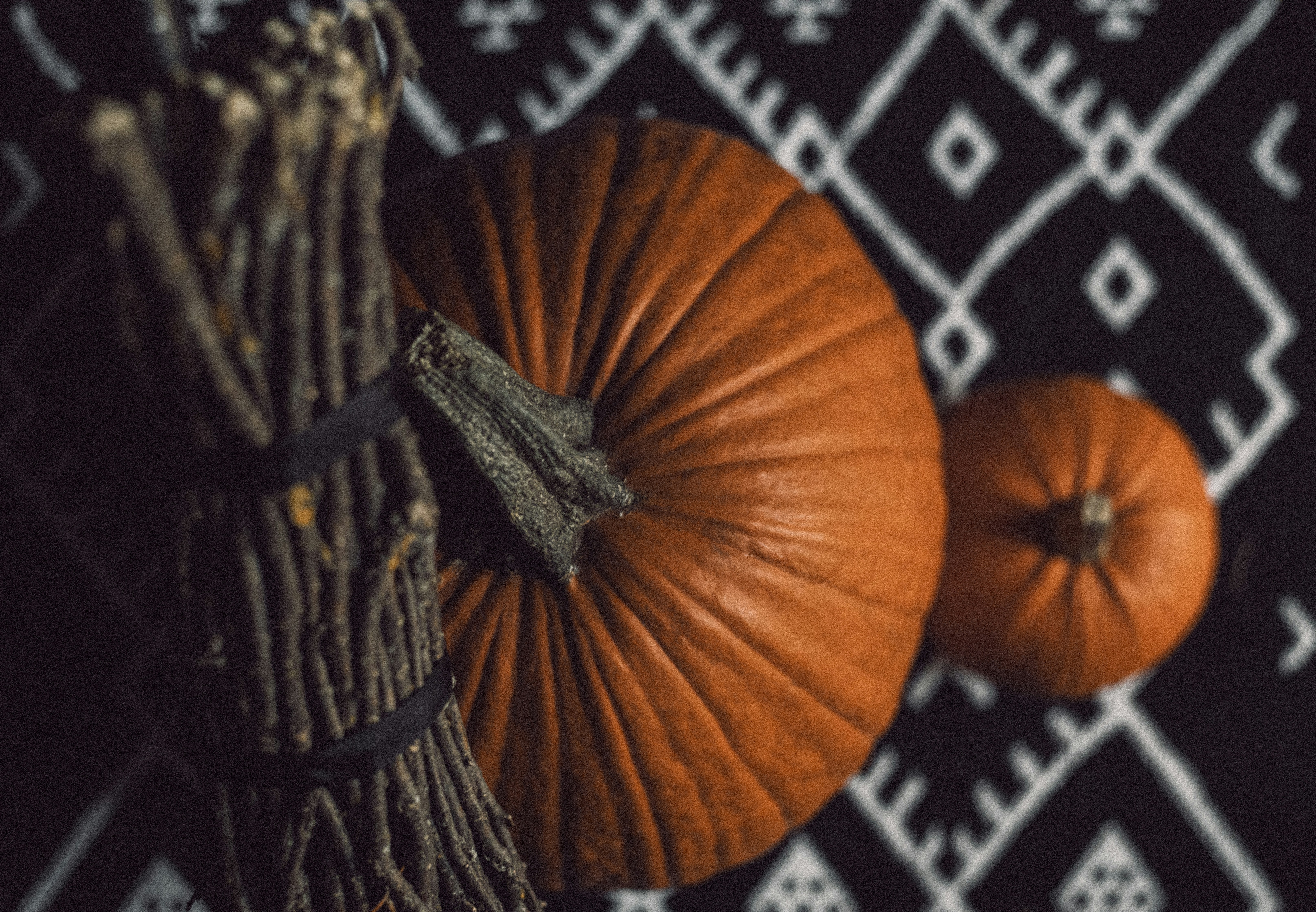 Two pumpkins and a broomstick on patterned background