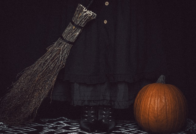 A witch's broom, pumpkin, and boots on halloween.