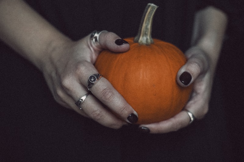 Dark nails holding a pumpkin