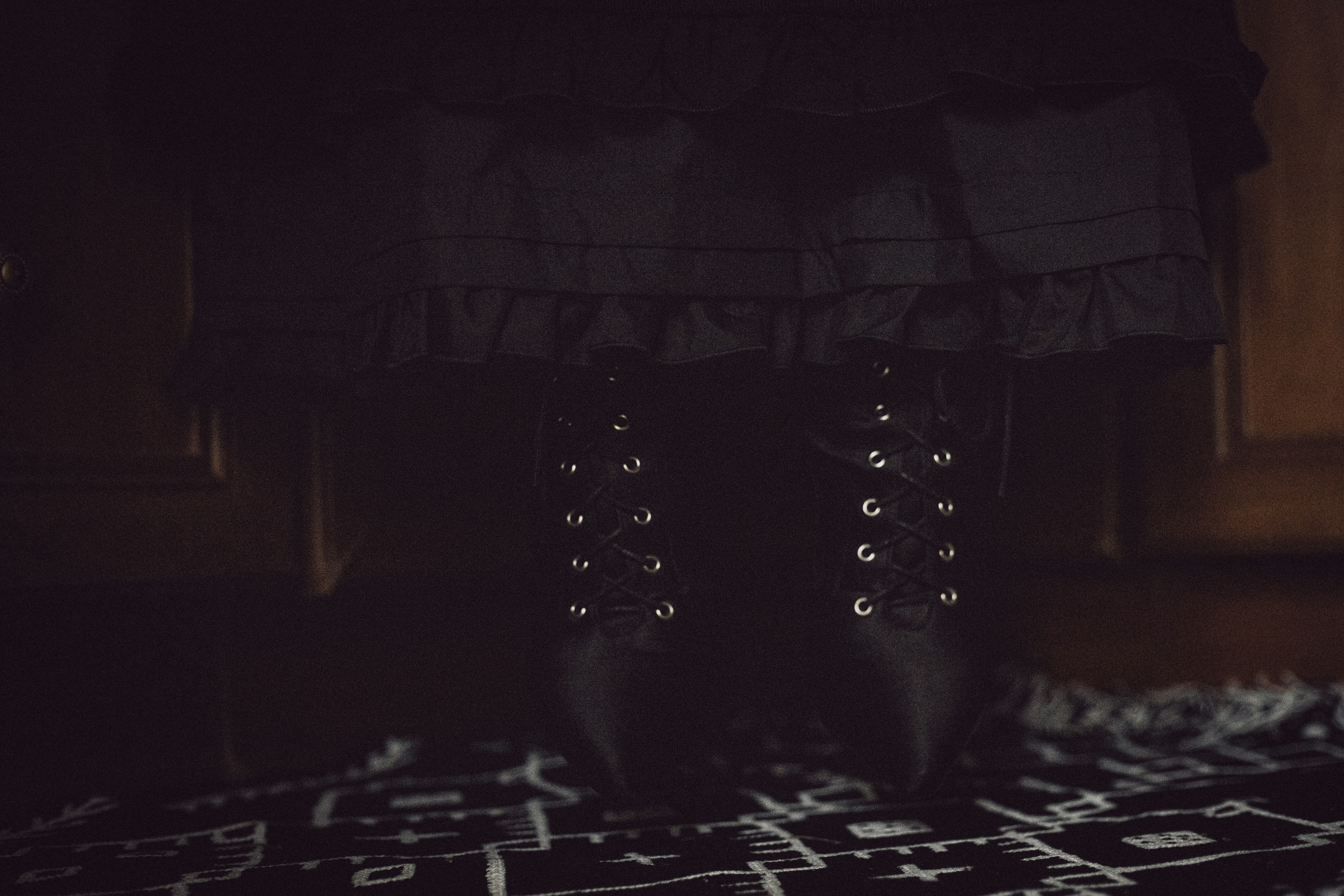 Black lace-up boots and ruffled skirt on floor.