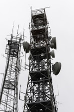 Two tall communication towers against a cloudy sky