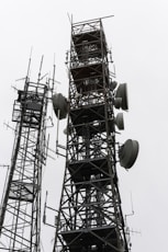 Two tall communication towers against a cloudy sky