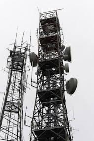 Two tall communication towers against a cloudy sky