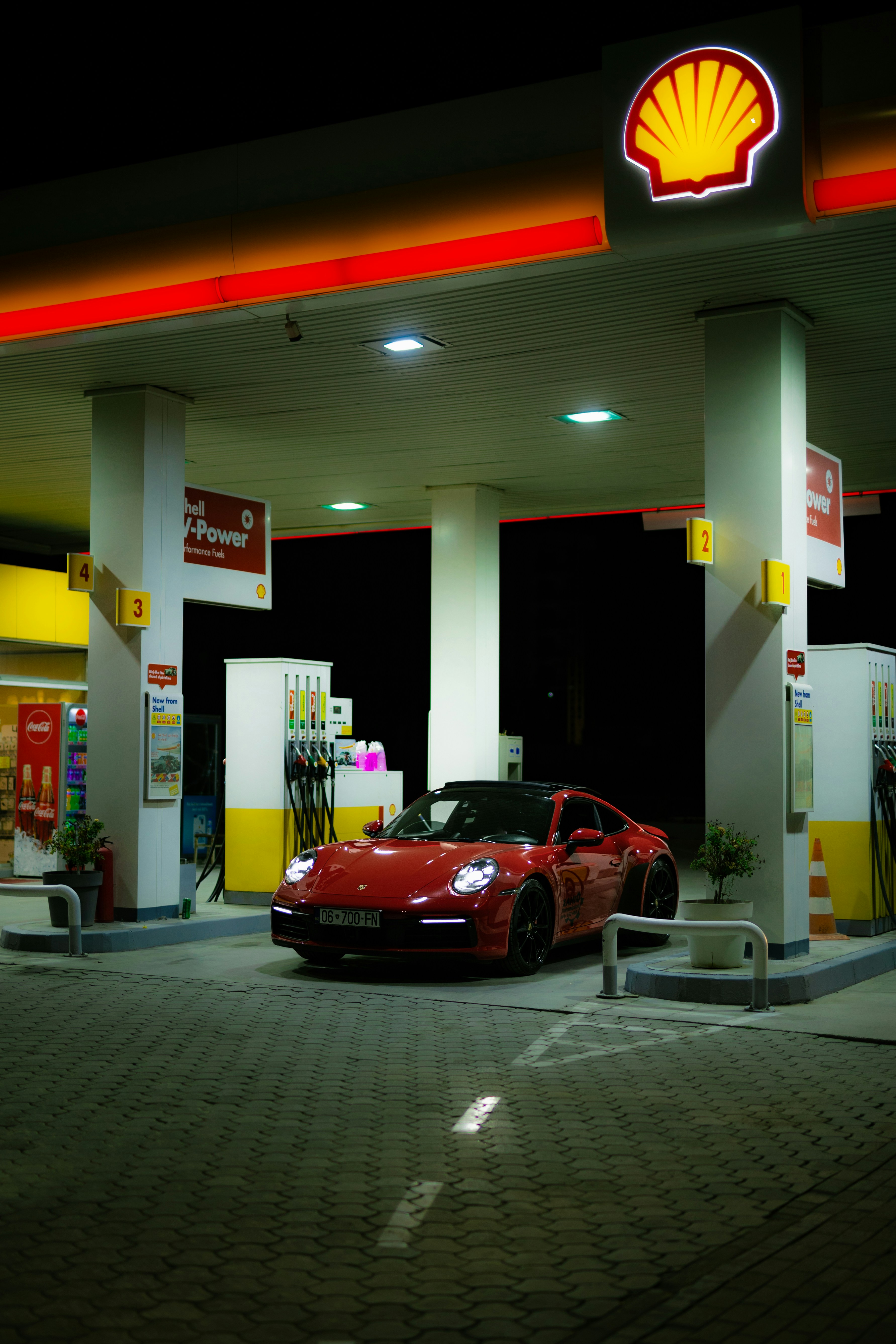 Mobil sport merah di pompa bensin shell di malam hari