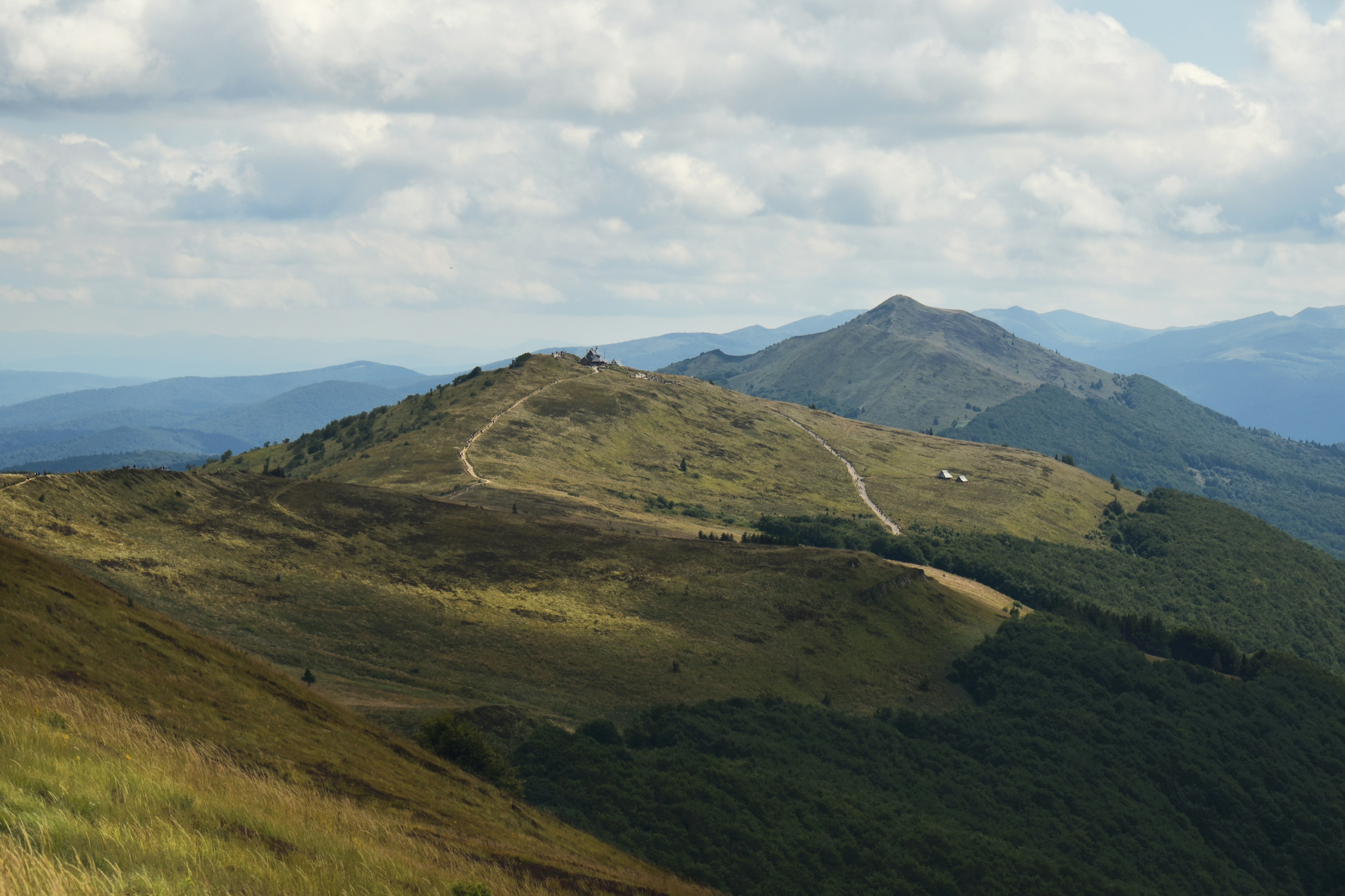 Rolling green hills with a path under a cloudy sky