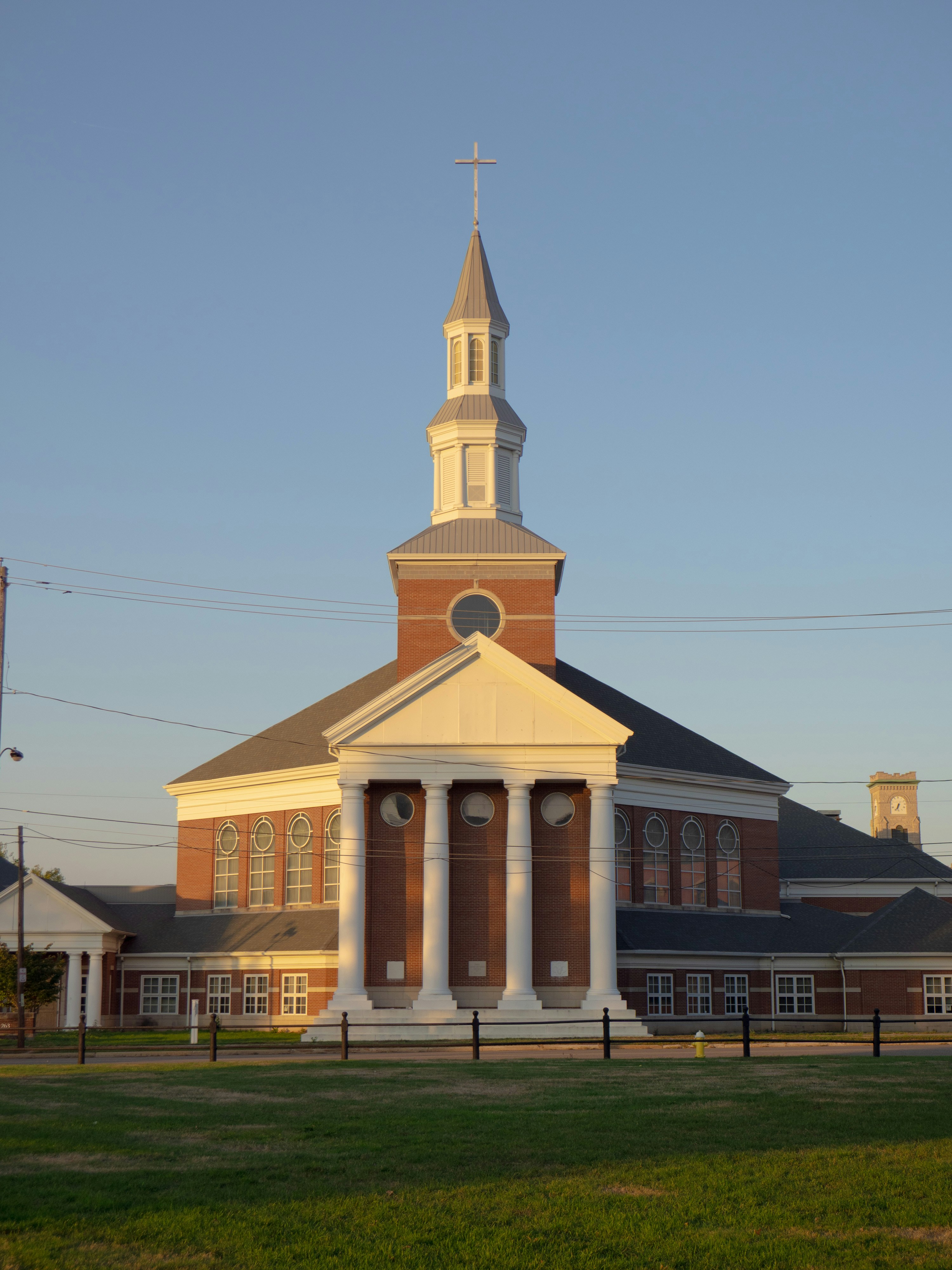 Una gran iglesia de ladrillo con columnas blancas y campanario.